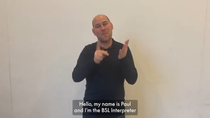 Paul, the Get Happy BSL interpreter signs against a grey background. 