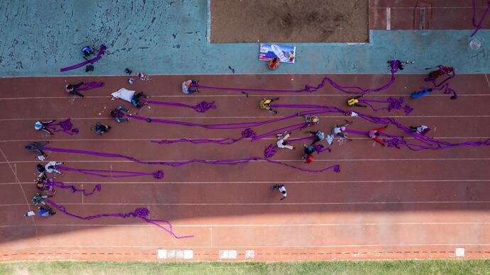 workers in a football stadium assemble a large purple piece of material