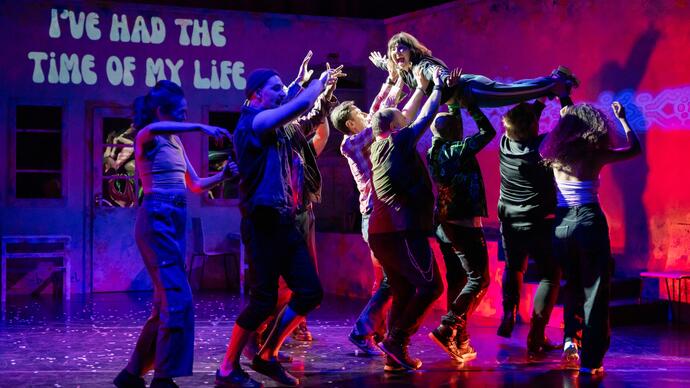 Members of the ZooCo ensemble lift a performer high in the air 'dirty dancing style' as the words 'I've had the time of my life' are projected onto the back wall of the stage.