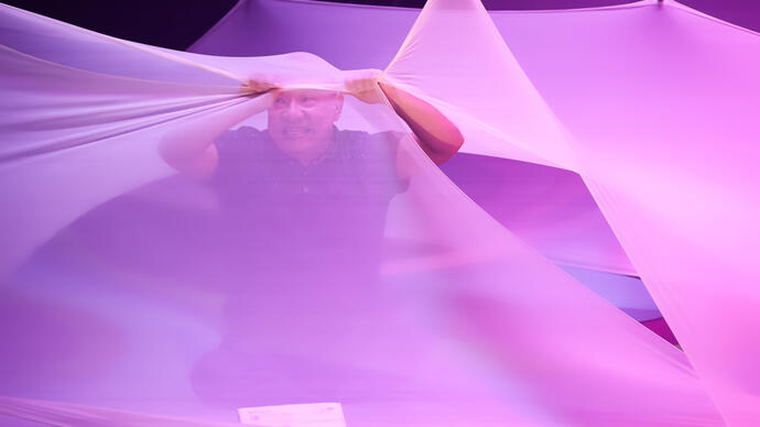 A perform looks frustrated as they act among pieces of large white draping fabric.