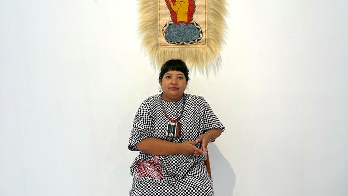 The artist sits in front of a portrait