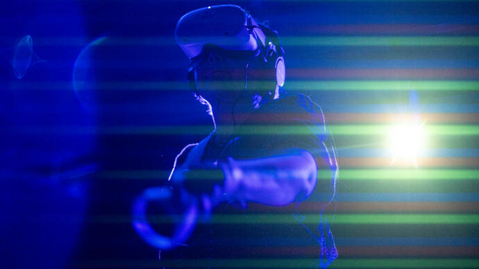A person dances with a VRF head set on, surrounded by blue and green lights