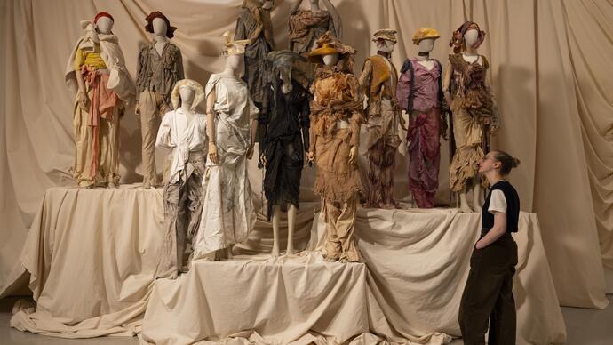 A woman looks at a collection of earth-toned outfits by designer Paolo Carzana.