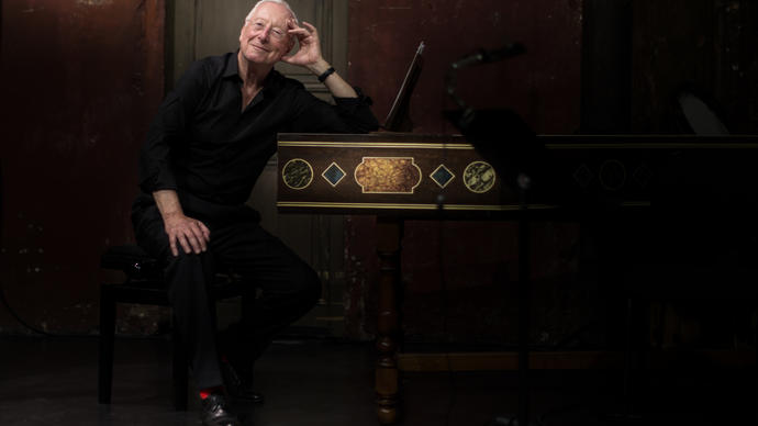 Image of conductor William Christie by a harpsichord