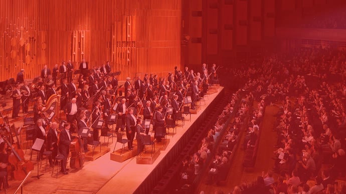 an orchestra playing classical music in the barbican hall in central london