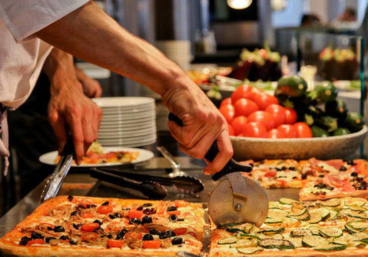 Photo of man cutting a slice of pizza