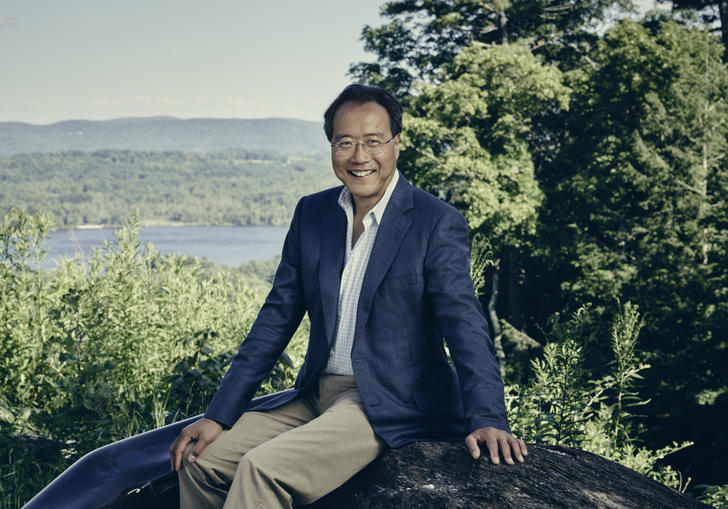 Yo Yo Ma sitting on a rock