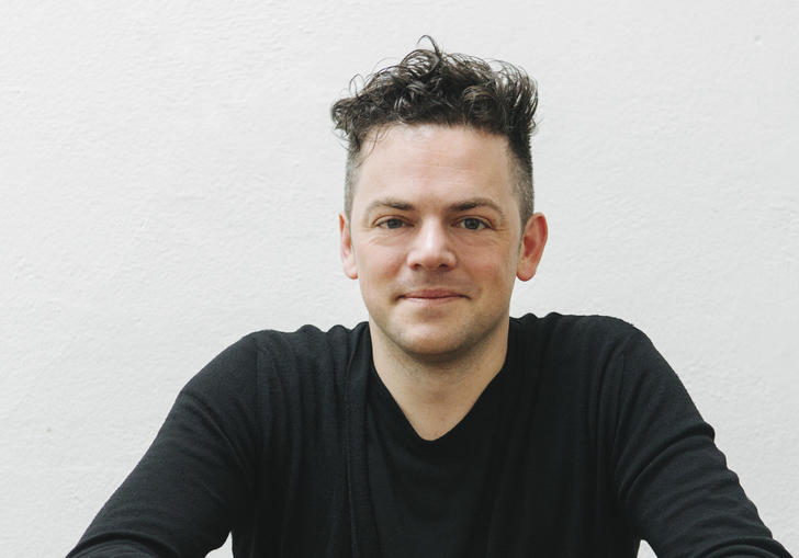 Nico Muhly sitting at desk 2017