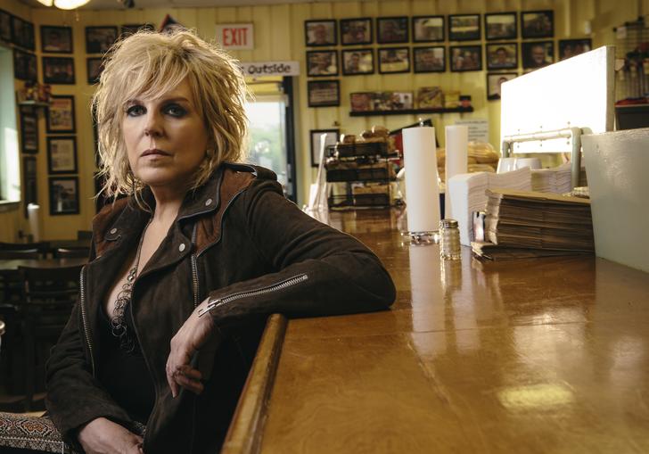 Lucinda Williams leaning one arm on the counter at a diner