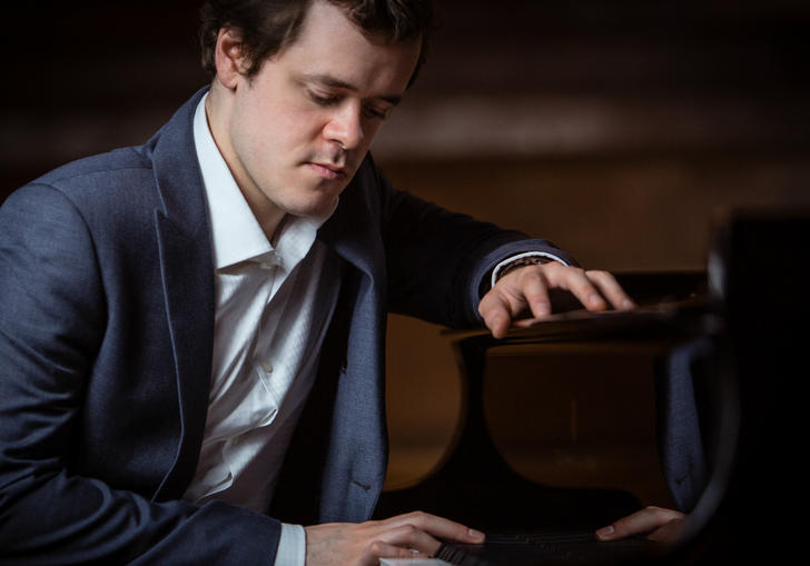 Benjamin Grosvenor sitting at a piano 2019