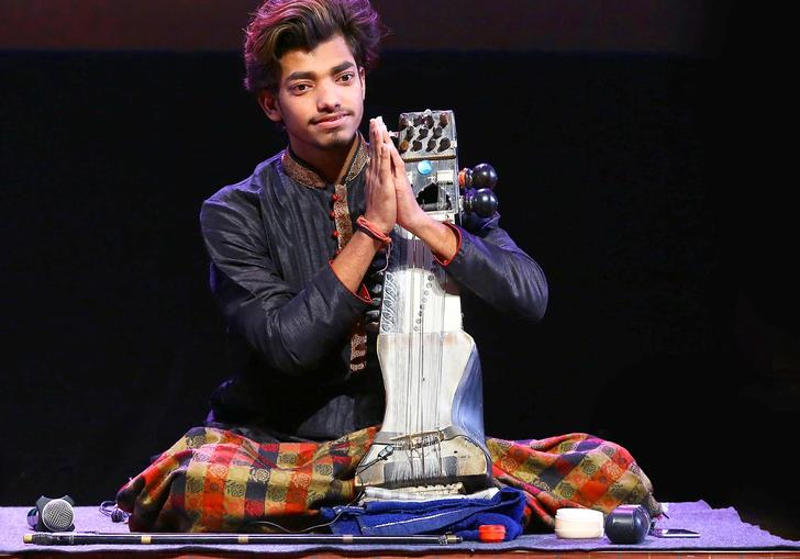 Momin Khan presses his hands together, seated on stage