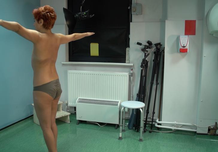 An undressed woman waiting to be looked over by a doctor in her hospital room.