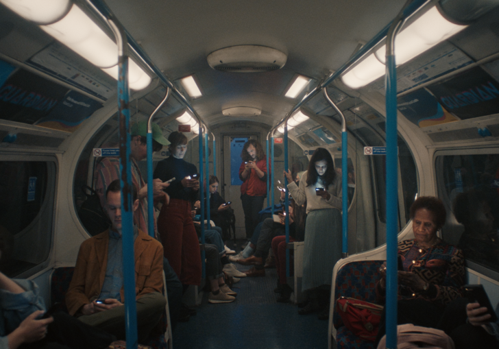 Group of people on underground train all looking at their phones