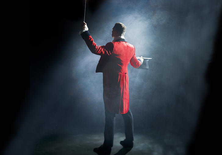 A circus ringmaster standing in a spotlight