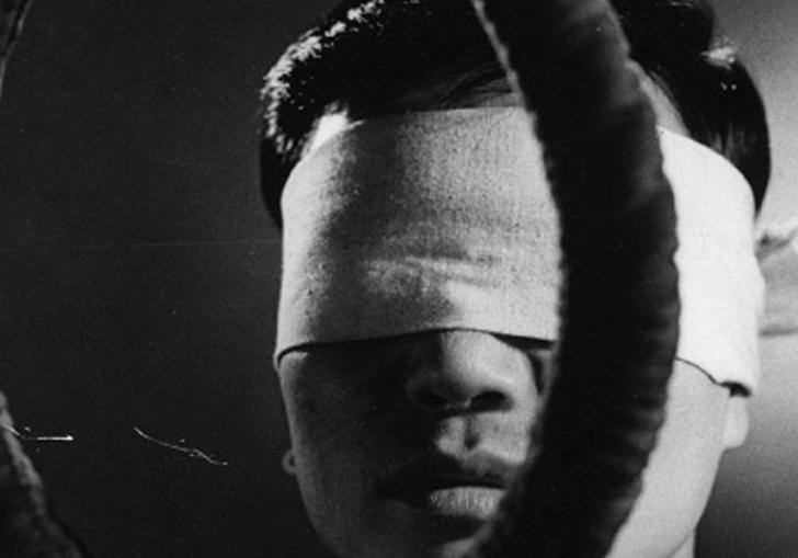 blindfolded man standing behind a noose