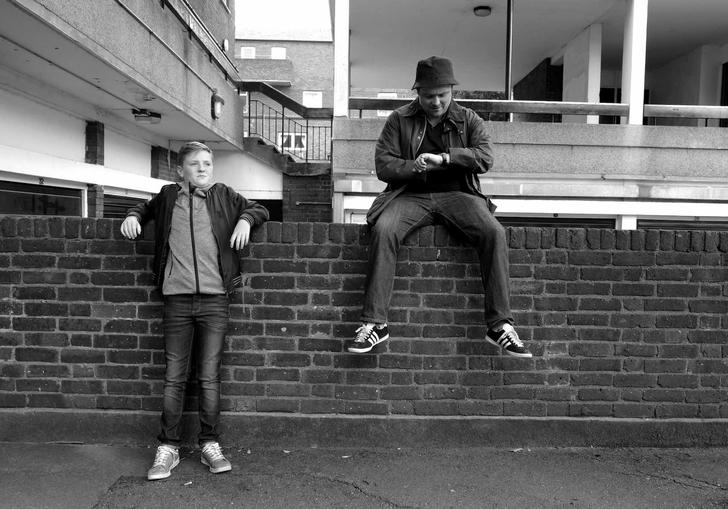 black and white image, two boys one sitting on a wall one standing next to the wall