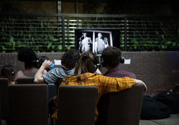 Couple sitting together with arm around each other, watching a TV screen.