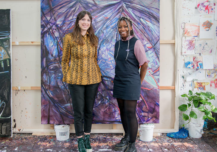 Two women standing in front of a purple painting