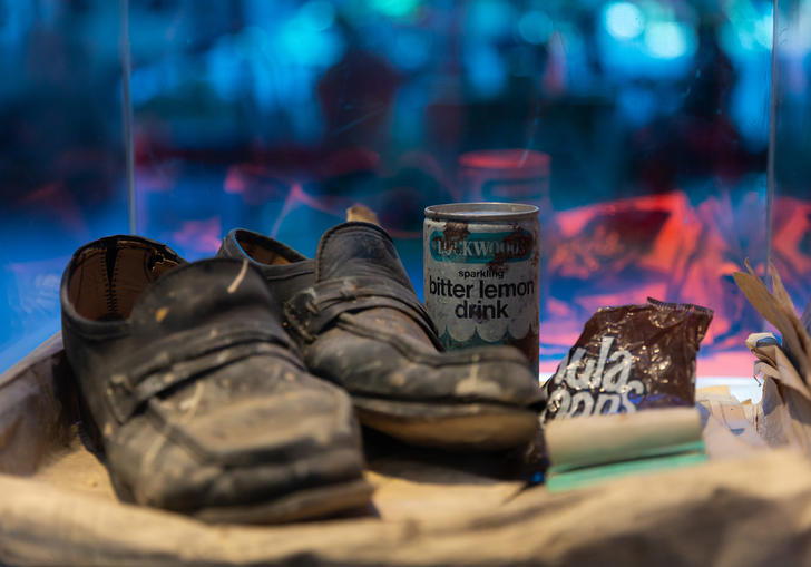A pair of dusty shoes, old lemonade can and packet of crisps in a cabinet