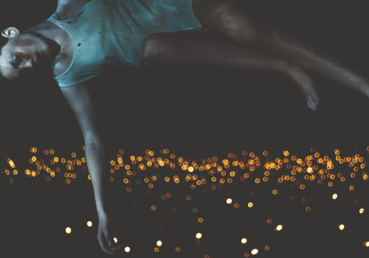 A woman lying horizontally above a city of lights