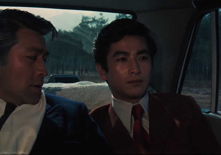 two men sitting in a dark car together
