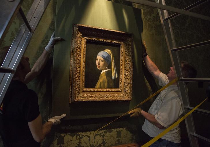 two people putting up the girl with the pearl earring painting