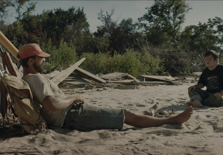 shia labeouf and zak sitting on a beach looking at each other