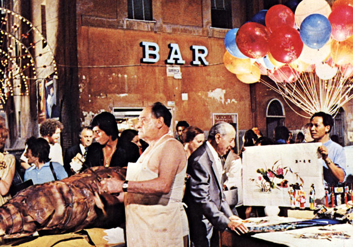 a market in a Rome square, there are balloons, meat and tables with people milling around