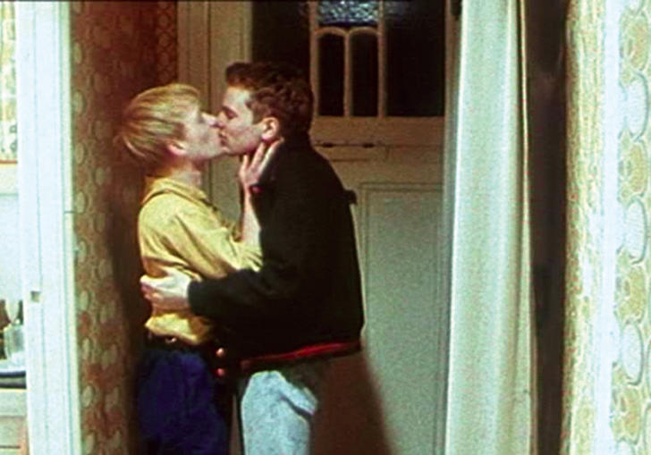 Two men kiss in a 1980s hallway in East Germany, in Wieland Speck's Westler