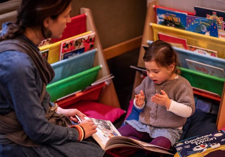 a young girl reads a picture book with her mum
