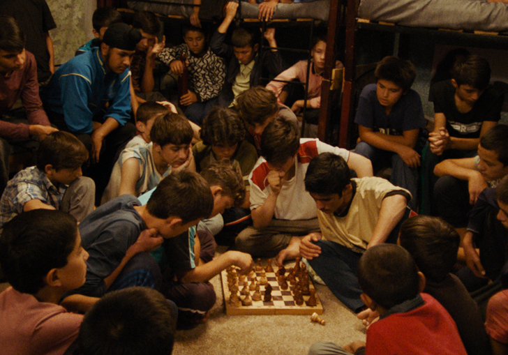 A large group of young boys play chess in The Orphanage