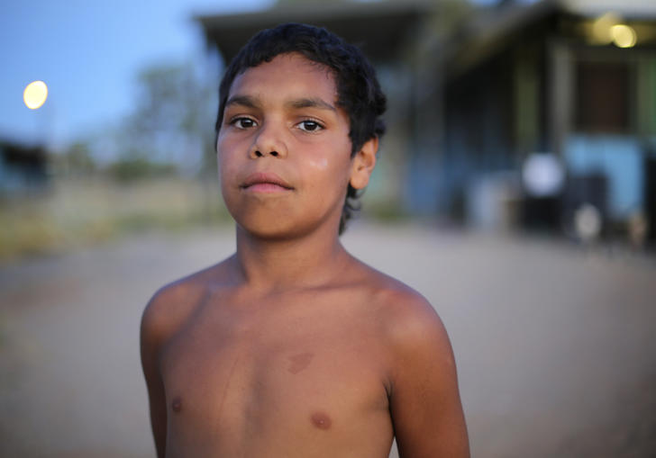 A young shirtless boy looks directly into the camera