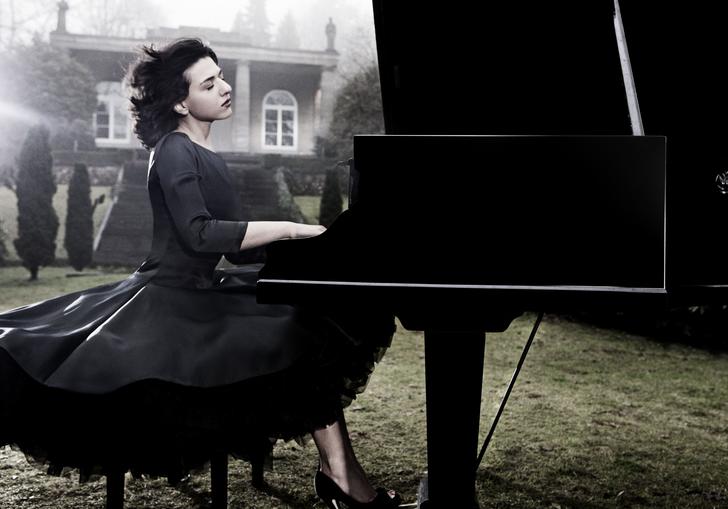 An ethereal image of Khatia in a stately garden with wind in her hair, expertly playing the piano with great emotion