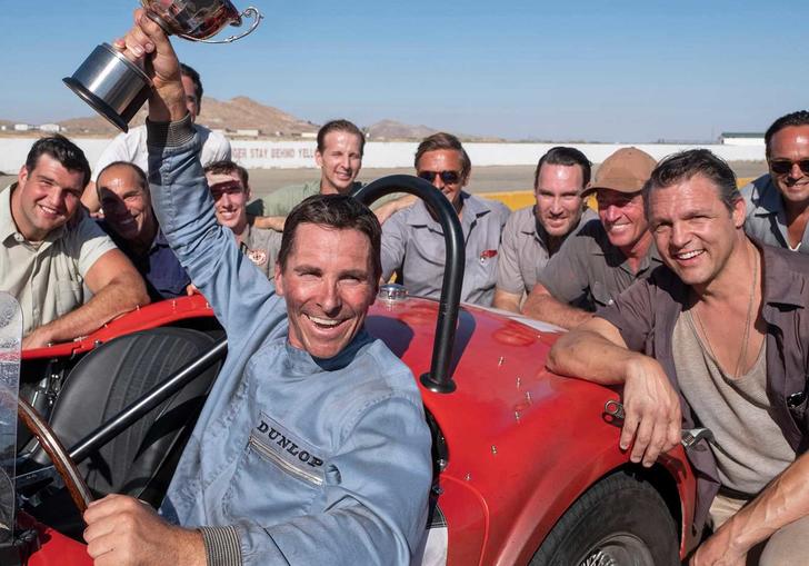 christian bale in Le Man 66 holding a trophy aloft sitting in a red car