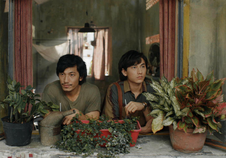 two young men looking out surrounded by plants