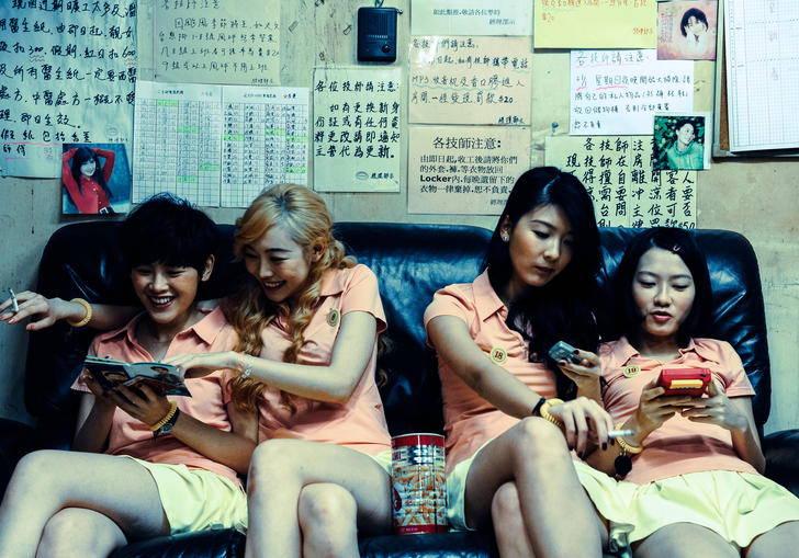 four young women sit on a sofa laughing together