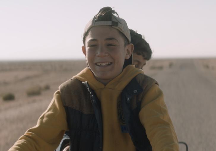 two boys on a motorbike riding along a road