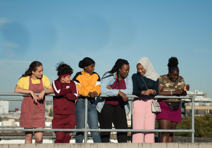 A group of girls stand in a line talking and laughing