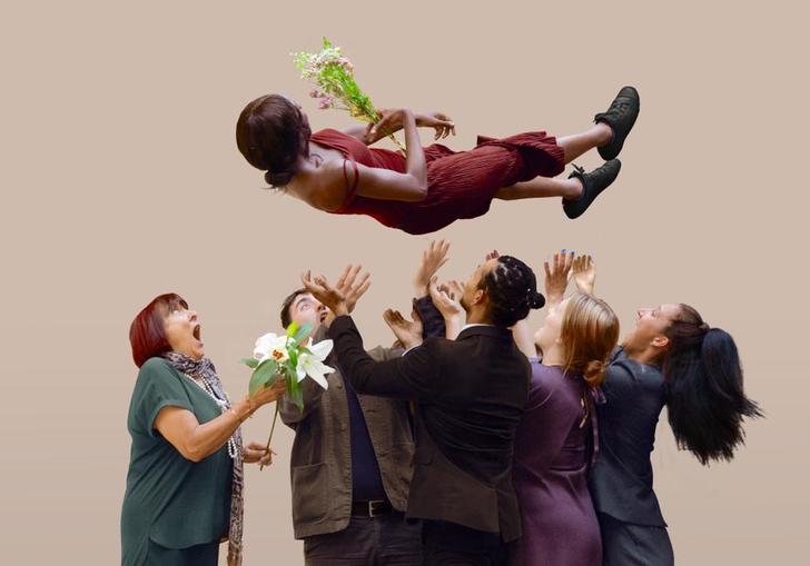 Five people launch a person into the air, as she holds a flower bouquet