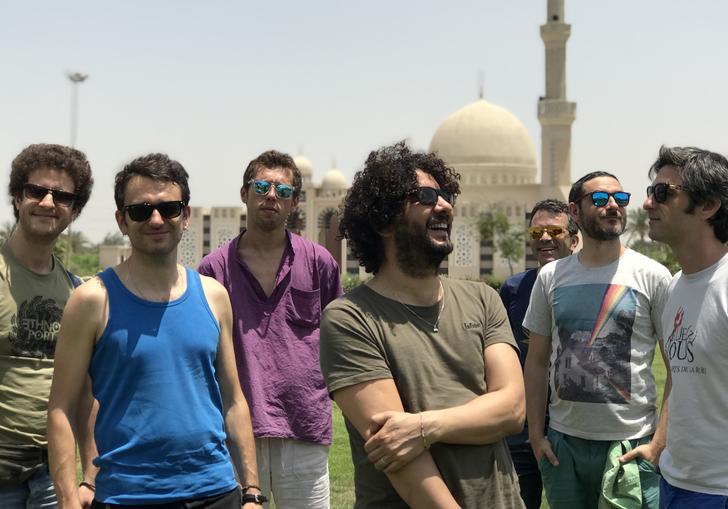 Sofiane Saidi & Mazalda standing in front of a mosque, wearing sunglasses in the sunshine