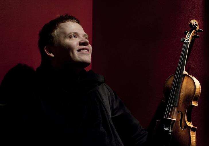 Pekka smiling joyfully as he gazes into the middle distance, violin in hand