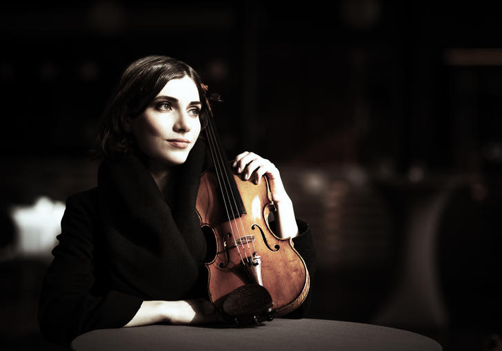 Diana staring intently into the middle distance as she poses tenderly with her violin