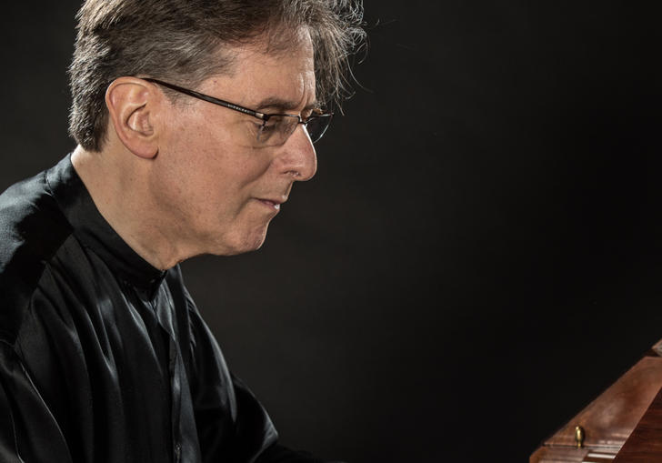 Robert Levin playing the piano, wearing a flowing black silk shirt
