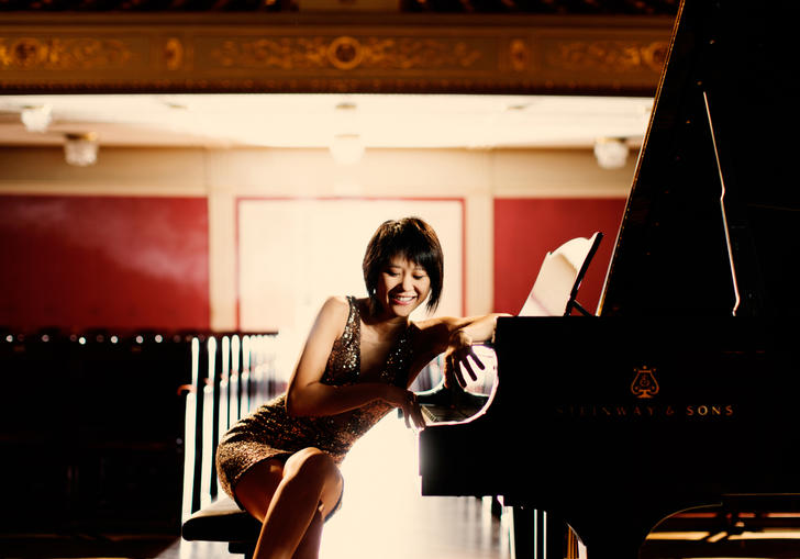 An playful image of Yuja sitting at her piano, facing the camera 