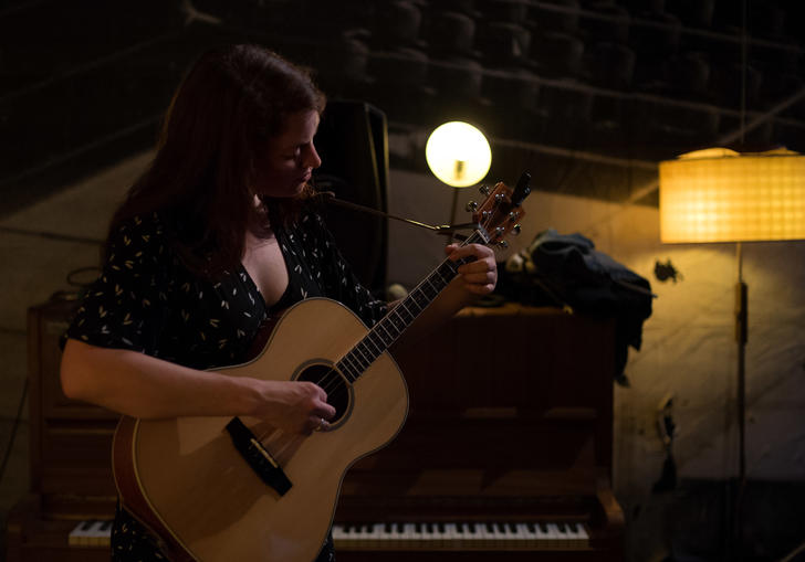 Fini Bearman playing acoustic guitar next to piano