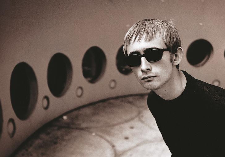 Black and white photo of Neil Hannon in a retrofuturistic room with black circular windows