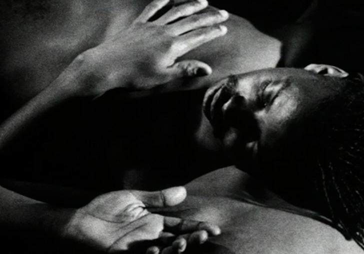 A young man lies down in a restful pose in black and white