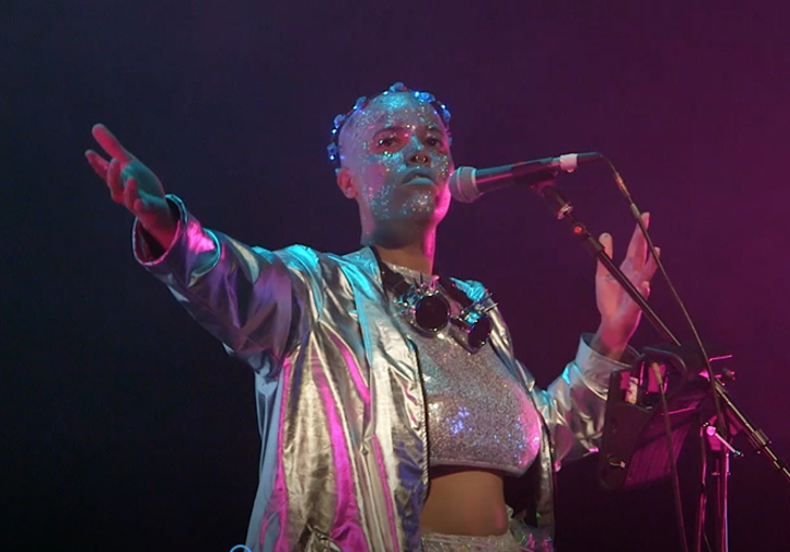 photo of a performer wearing glitter and holding a microphone