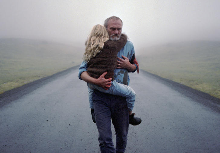 A man carrying a young girl along a deserted road