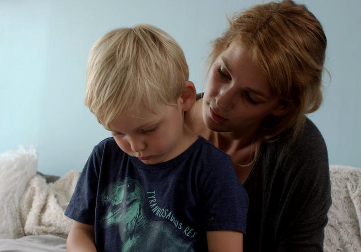 child sitting on woman's lap looking downwards